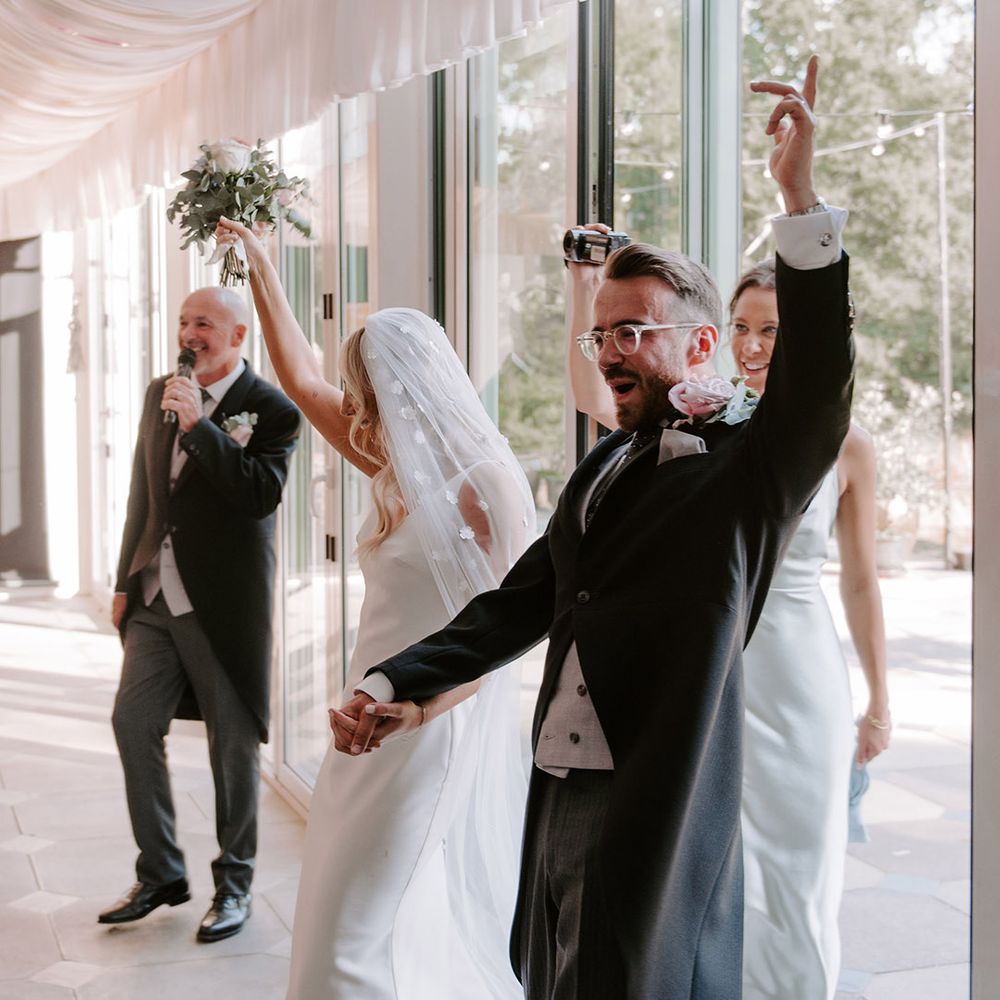 Bride and groom enter their wedding reception with flower applique veil