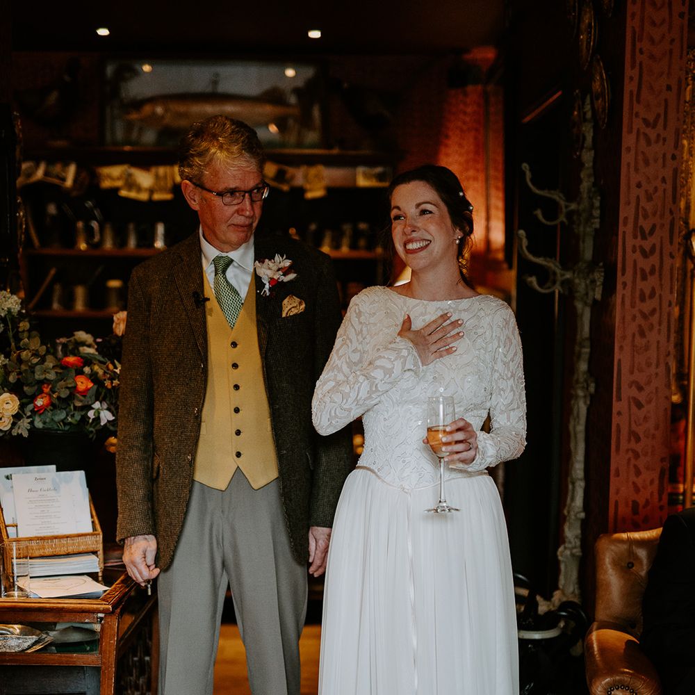 Bride in long vintage lace wedding dress with pearl necklace and pearl hair clips holding glass of champagne doing wedding speech at The Zetter Townhouse