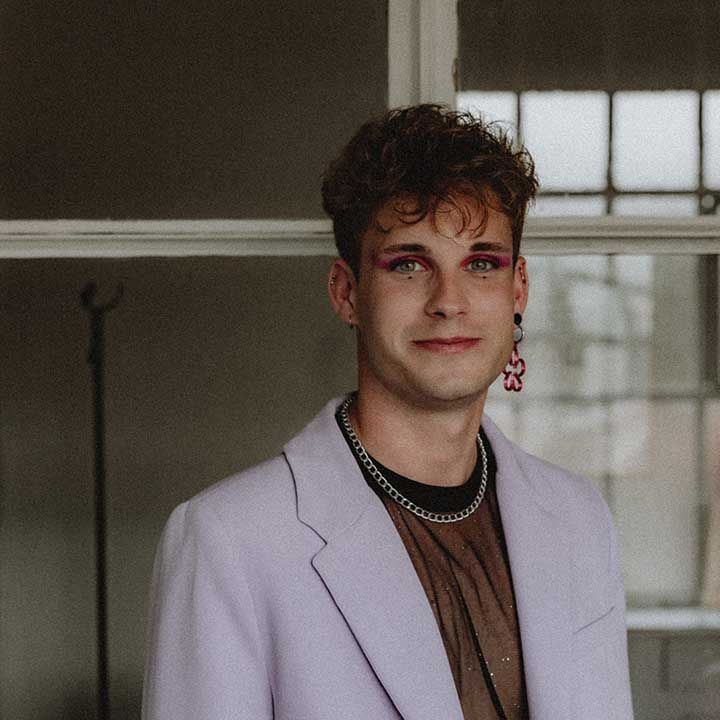 Wedding guest wears pastel purple suit complete with pink eyeshadow and floral earring