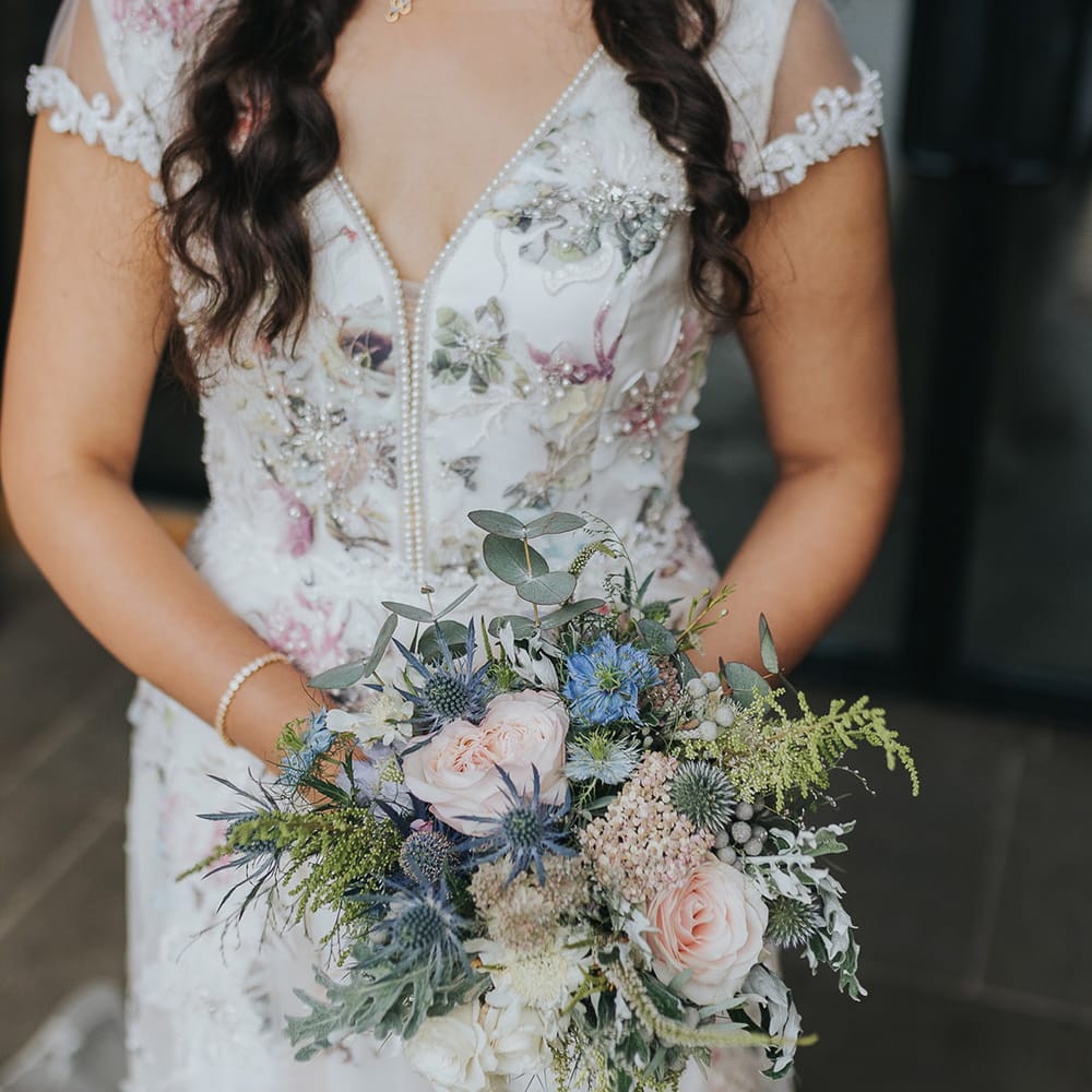 Floral wedding dress and seasonal wedding bouquet with pink roses and thistles 