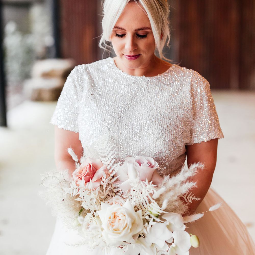 Short sleeve beaded bridal top with bridal separates wearing her hair in an updo with pink and white bouquet with pink ribbon 