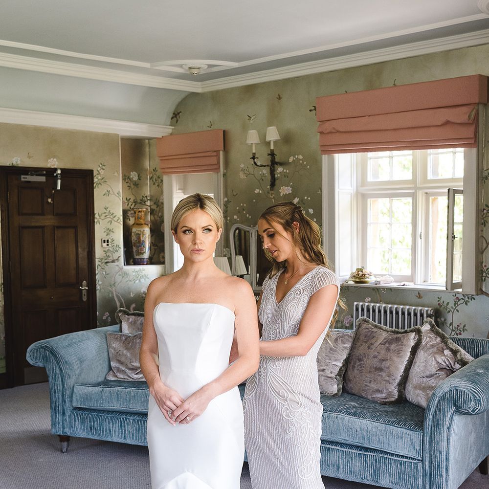 Bridesmaid in beaded bridesmaid dress does the bride's wedding dress up which is a fitted mermaid wedding dress 