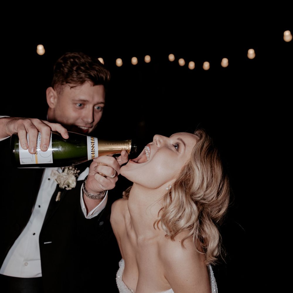 The groom pours champagne into the bride's mouth 