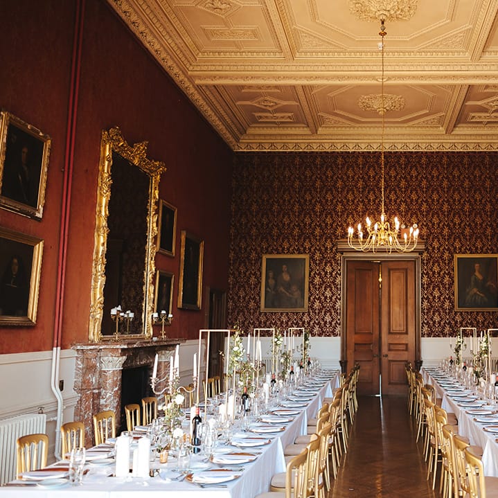 Classic wedding tablescape with white table cloth, tapered candles in gold candelabras, pillar candles, gold frame decorations, gold plates, gold cutlery and dried flower and white rose floral arrangements at Grittleton House 