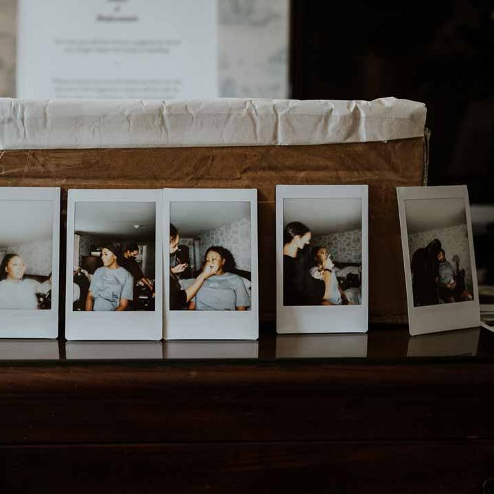 Wedding polaroid photos of bridal preparations lined up next to basket at Tredudwell Manor