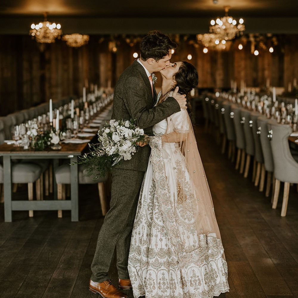 Wharfedale Grange wedding with the bride in a white and gold lehenga kissing groom 