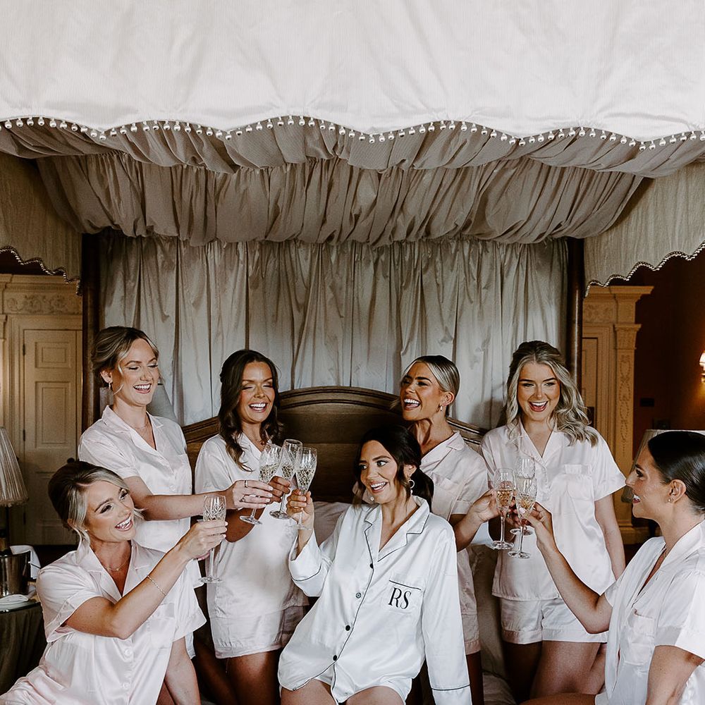 Bridal party in white satin pyjamas getting ready together on the morning of the wedding 