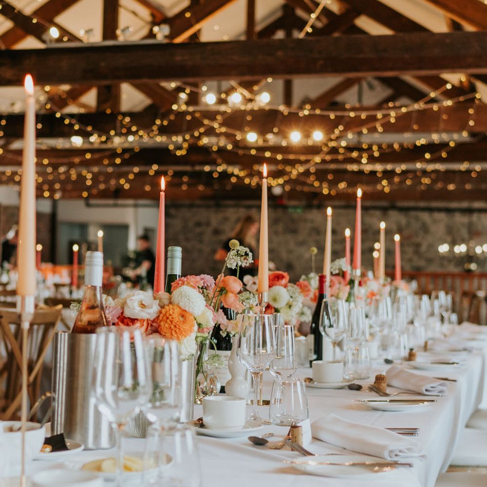 Pink and peach taper candles on rustic tablescape with fairy lights at The Wool Tower 
