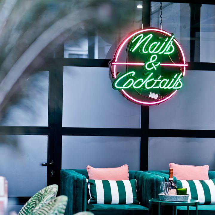 The salon interior at Beauty Club London including nail area with neon sign reading nails & cocktails