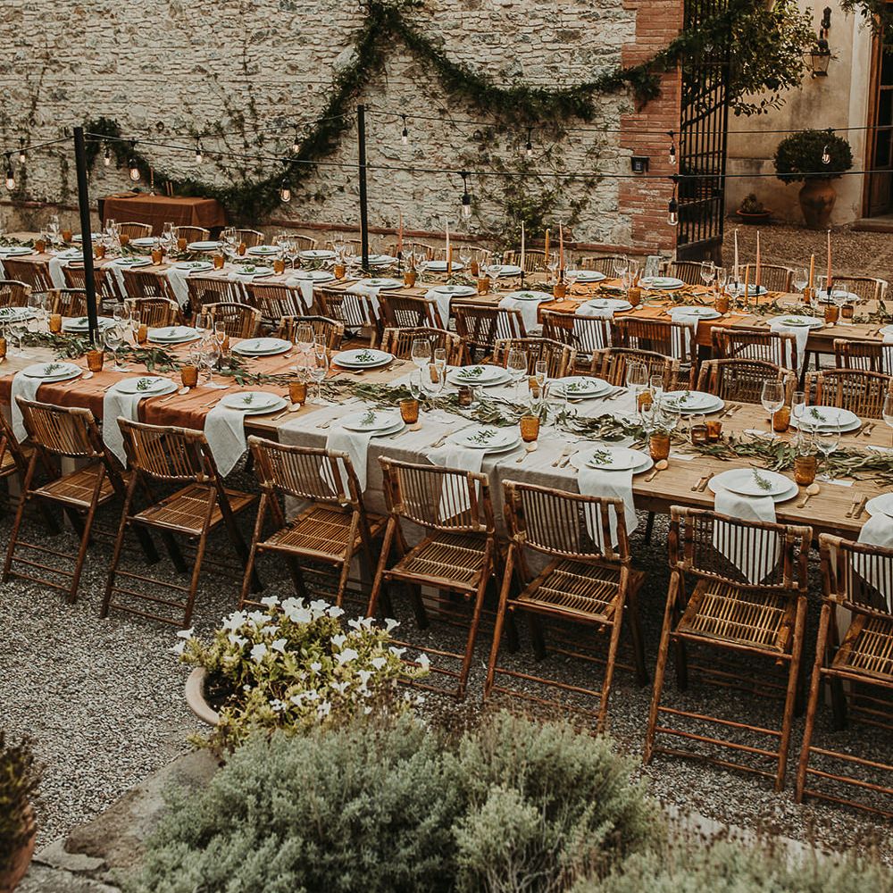 Wooden banquet tables decorated with foliage and earthy toned linens and candles 