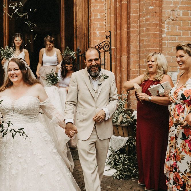 couple holding hands with olive bouquets thrown over them