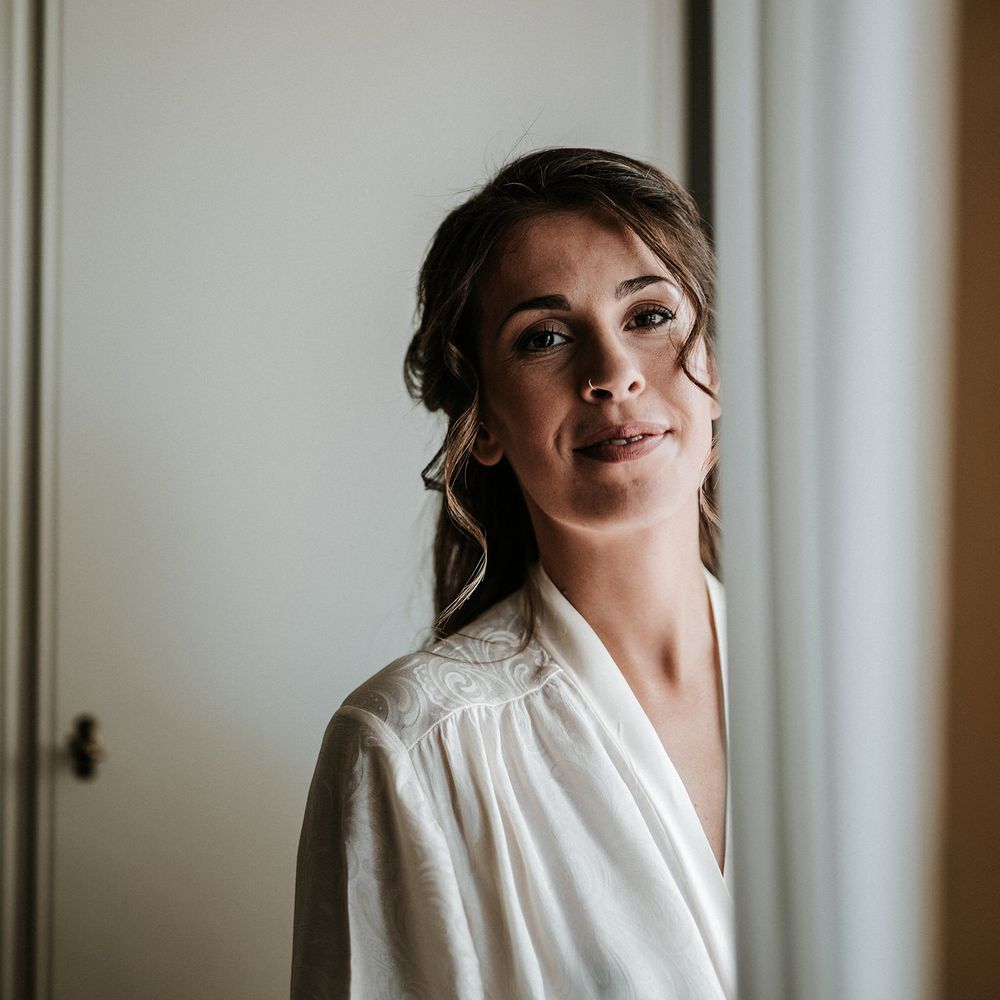 Bride with half up half down hair on the morning of the wedding in a white getting ready robe 
