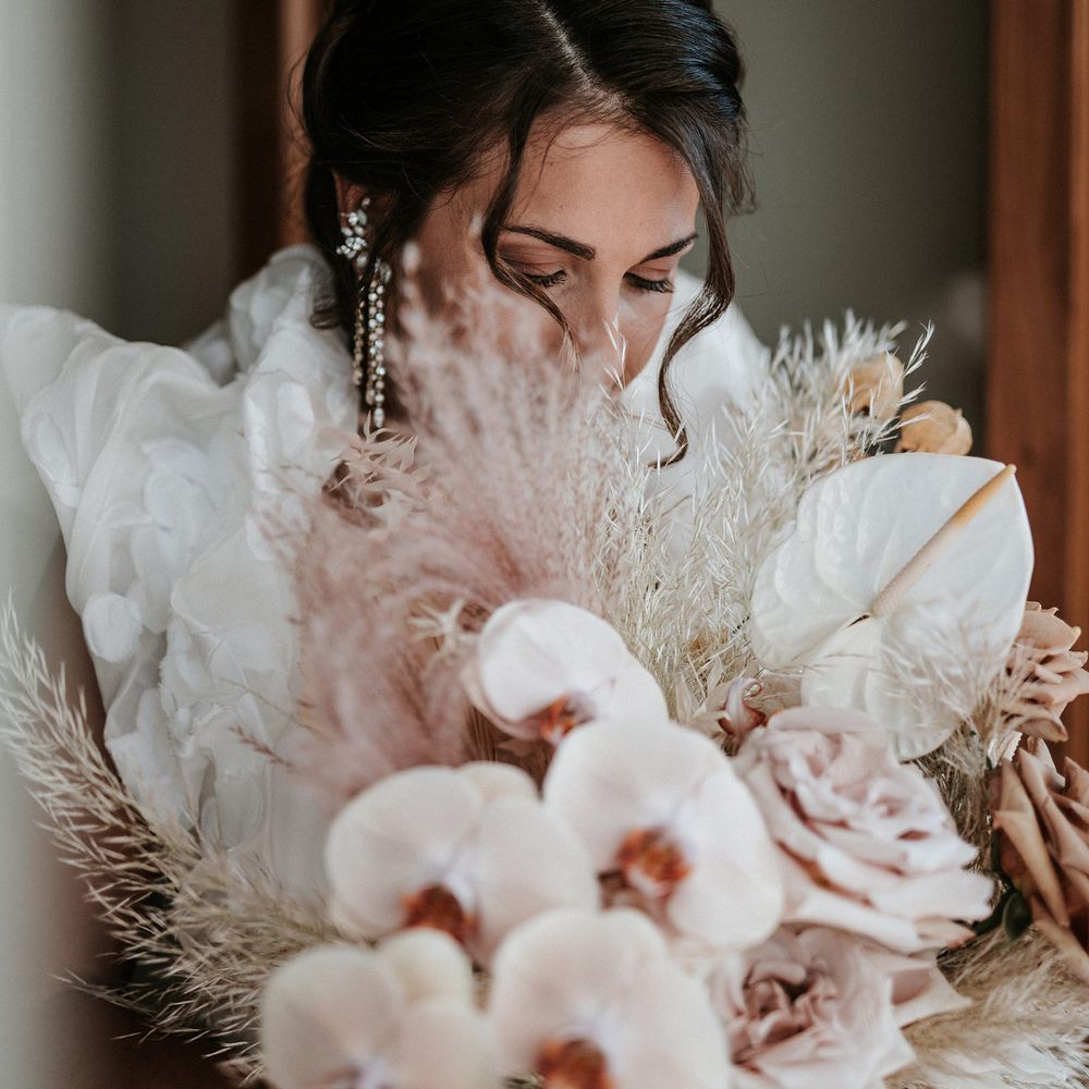 Bride holding her orchid wedding bouquet with anthuriums and dried grasses 