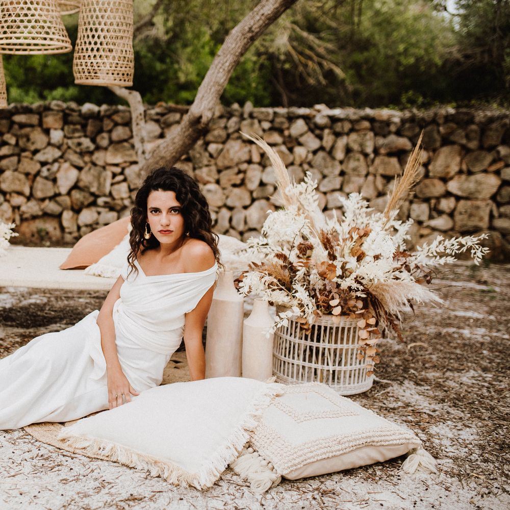 Bride sits outside with wicker lampshades and white pillows