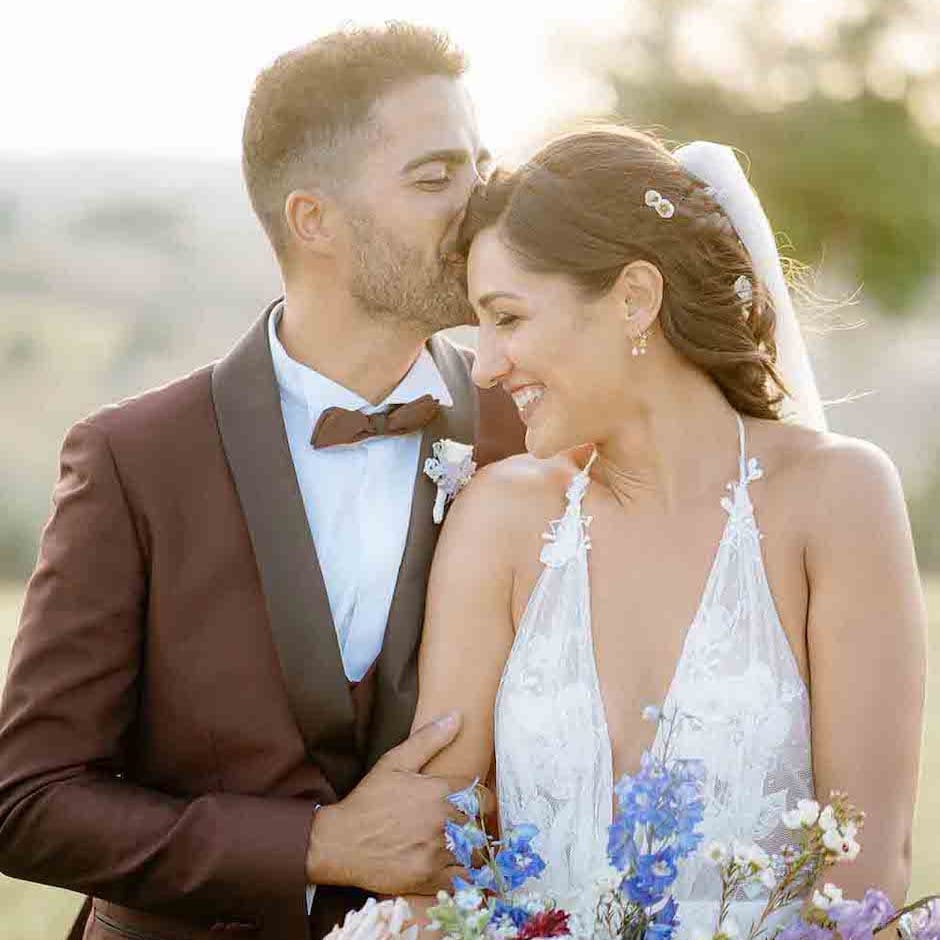Groom in maroon wedding suit with bride in halter neck wedding dress