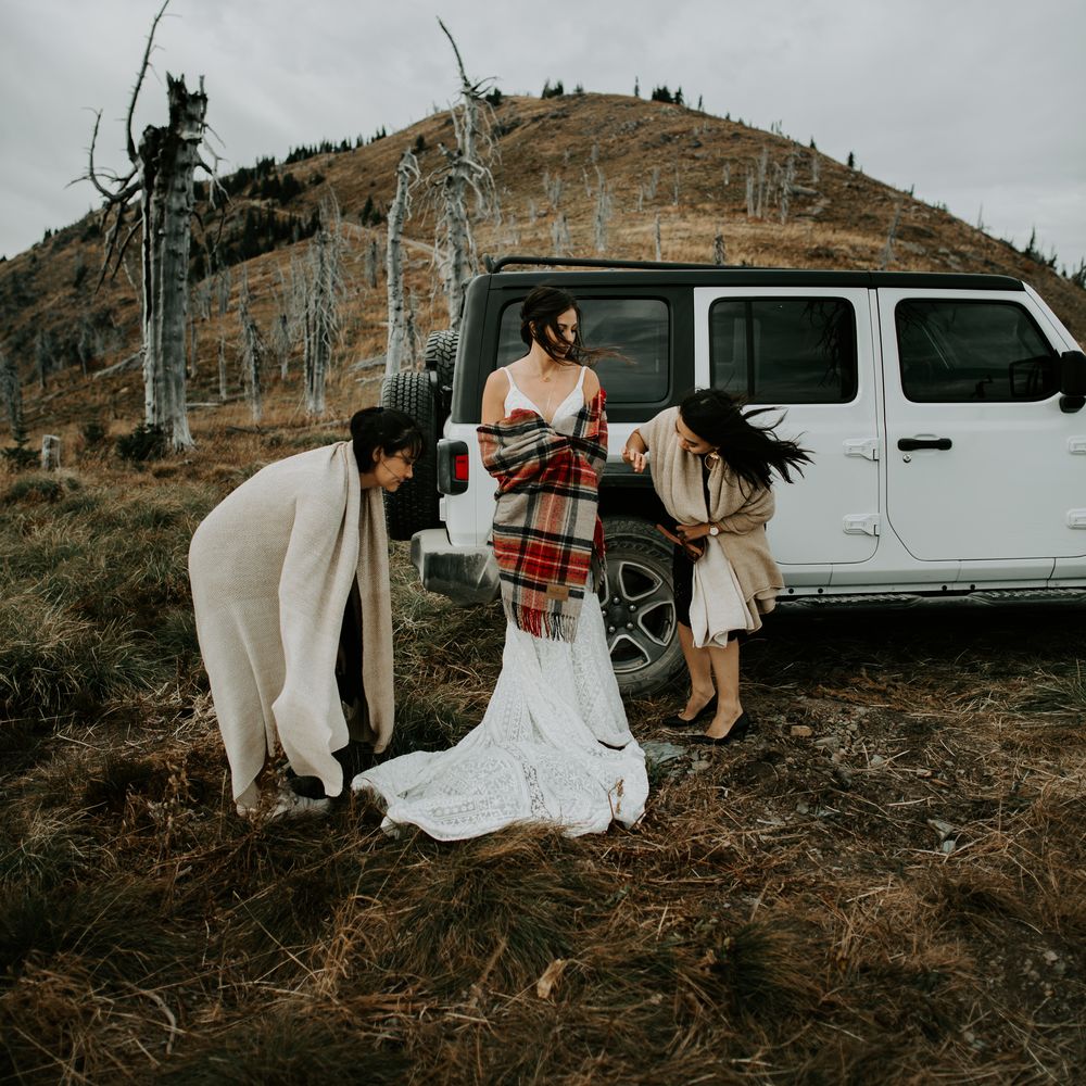 Bride gets ready before elopement ceremony wrapped in tartan blanket 
