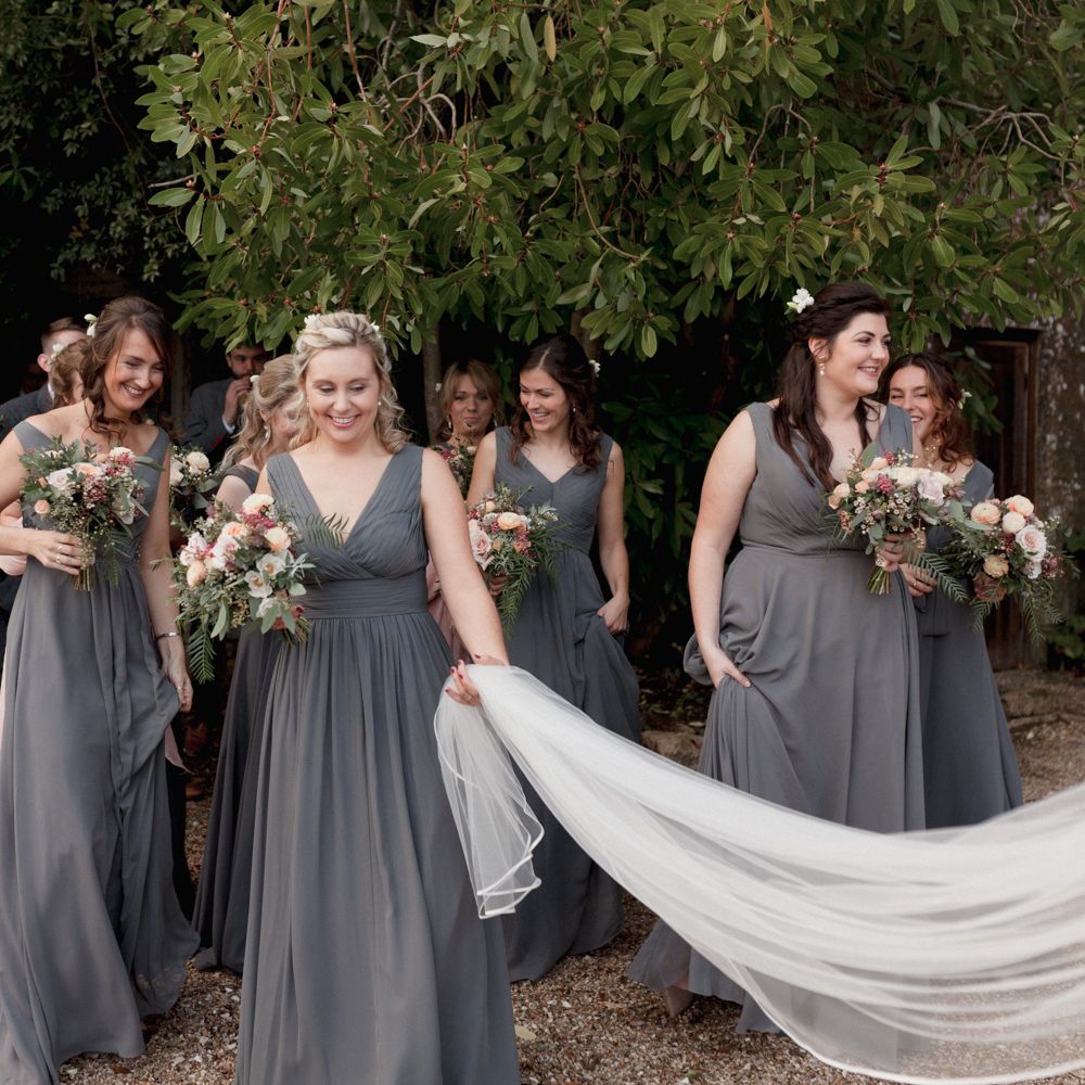 Bridesmaids holding brides sweeping veil with groomsmen in the background