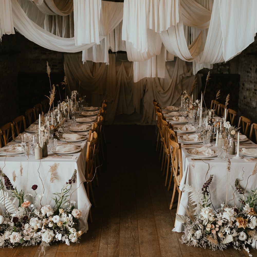 Intimate wedding reception at Pentney Abbey with draped ceiling, dried and fresh flower arrangements and taper candles 