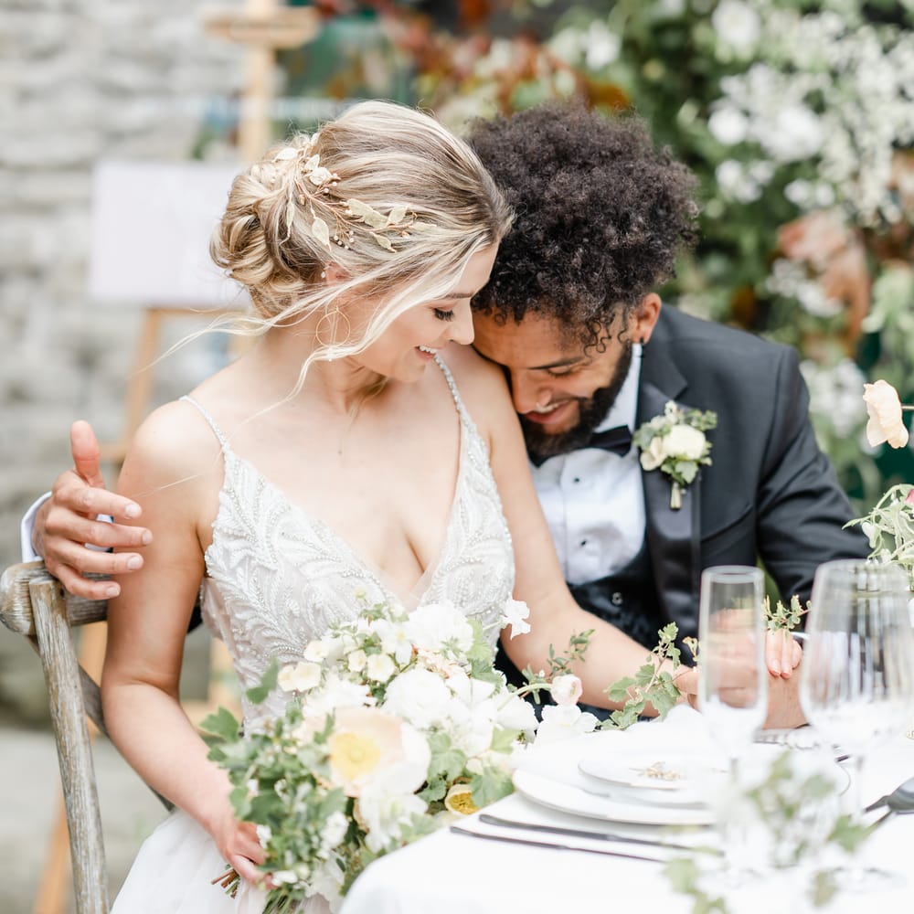 Bride with a loosely pinned up do wearing a laurel headdress and beaded bodice wedding dress with thin straps 