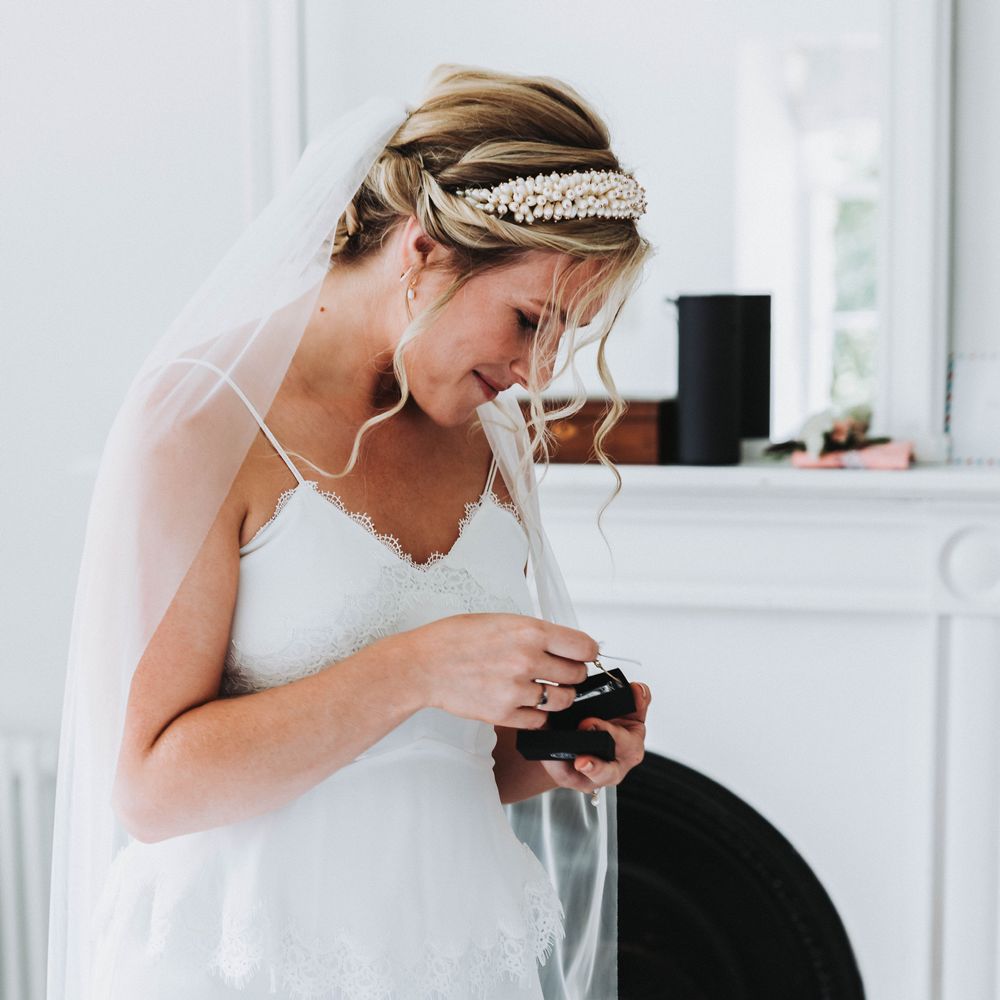Bride looks at wedding gift on her wedding day as she smiles 
