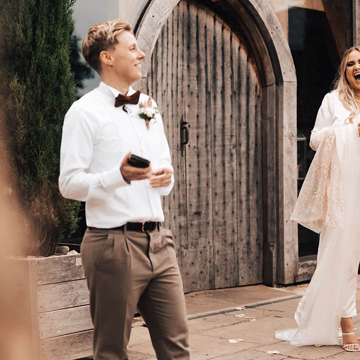 Brides laugh during speeches outdoors on their wedding day