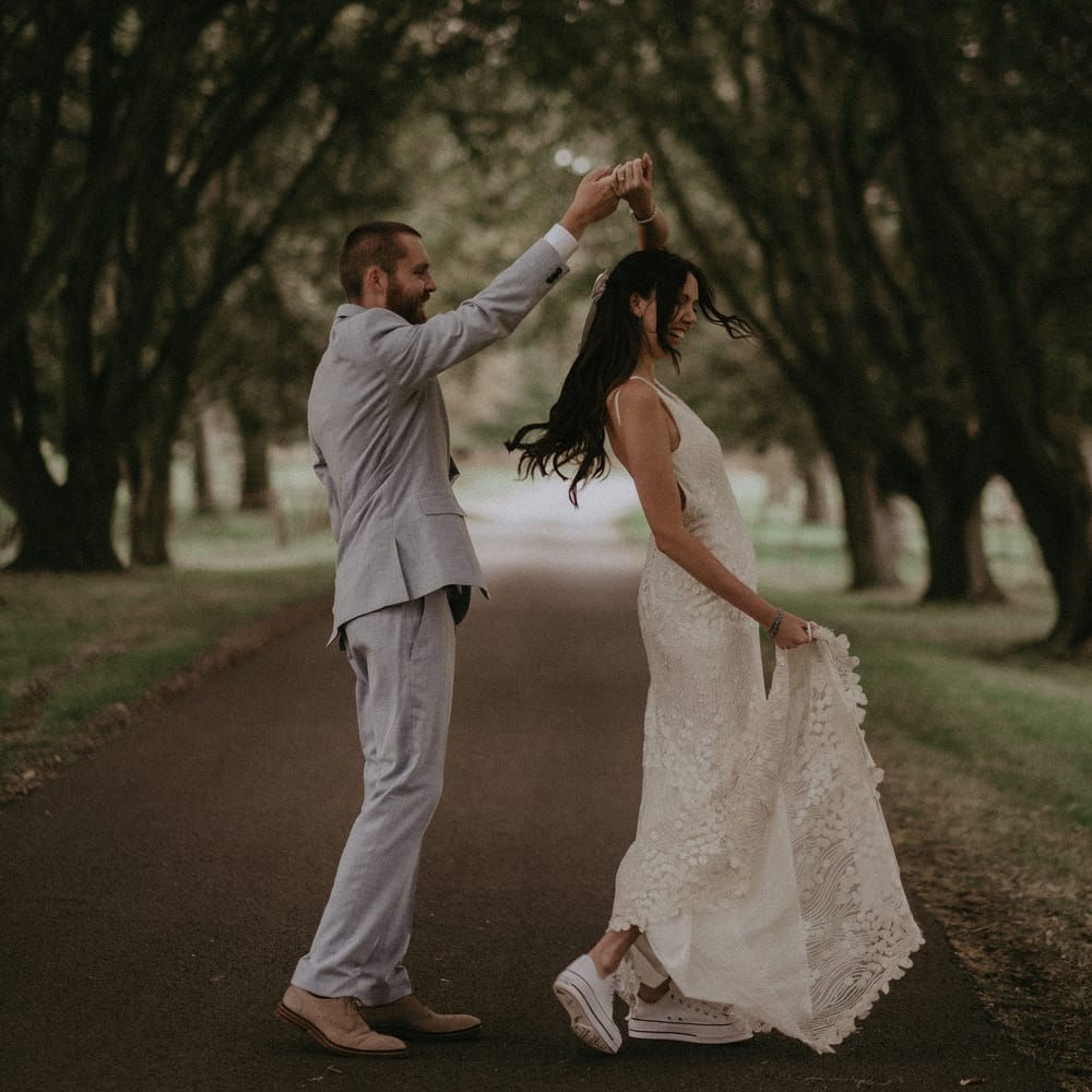 Bride in trainers dances in the grounds of country house with groom