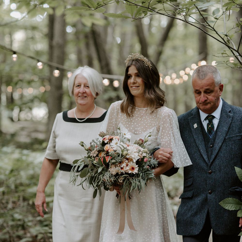 Bride walks down the aisle with her parents on wedding day