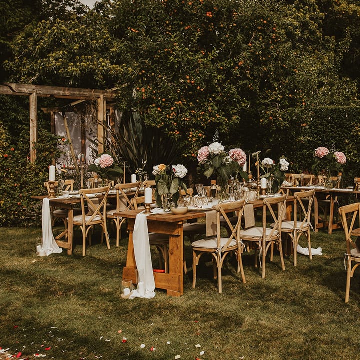 Garden reception setting complete with wooden tables for intimate reception