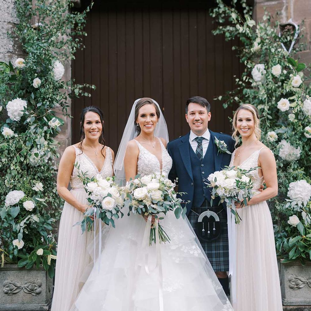 Classic Scottish wedding with bride in a layered princess dress, bridesmaids in white dresses and groom in a tartan kilt
