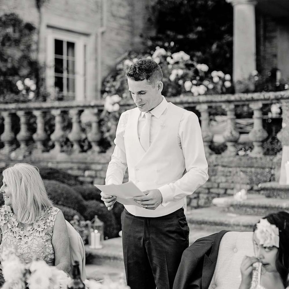Groom gives speech during wedding reception outdoors 