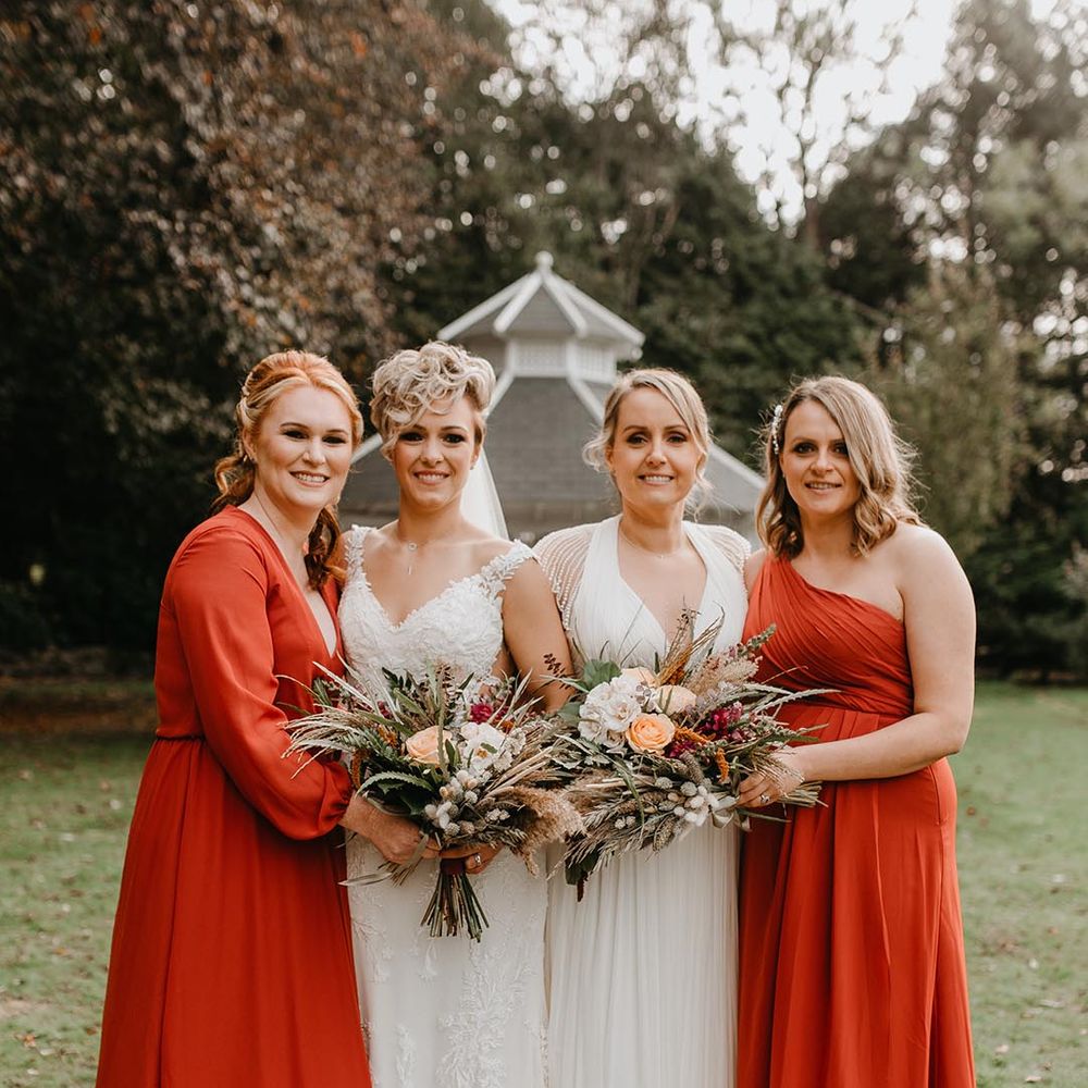 Bridal party with two brides and orange bridesmaid dresses