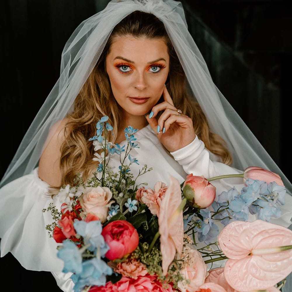Bride with coral eyeshadow wedding makeup and blue nails to match the vibrant wedding bouquet 