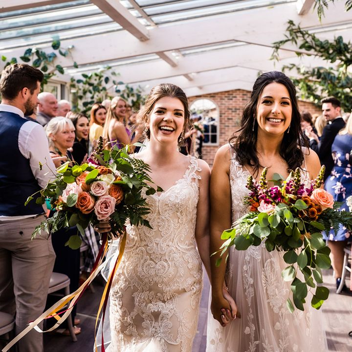 Brides in lace wedding dresses walk back down the aisle as a married couple