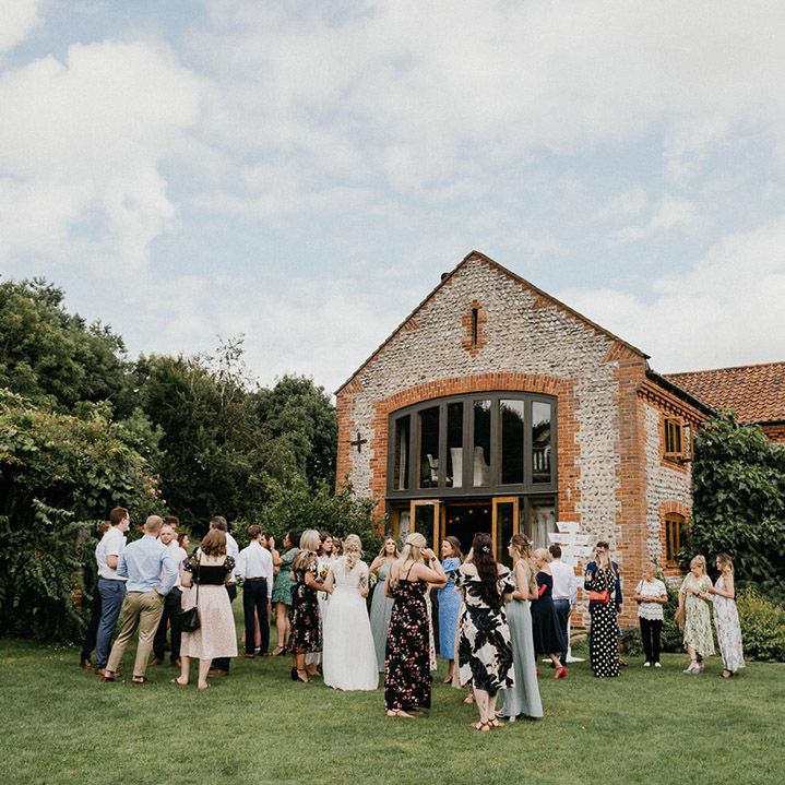 Wedding guests socialise outside Chaucer Barn wedding venue 