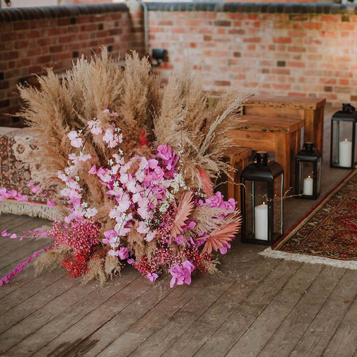 Prestwold Hal Barn wedding venue with wool rug, benches and pink cherry blossom and pampas grass floral arrangements 