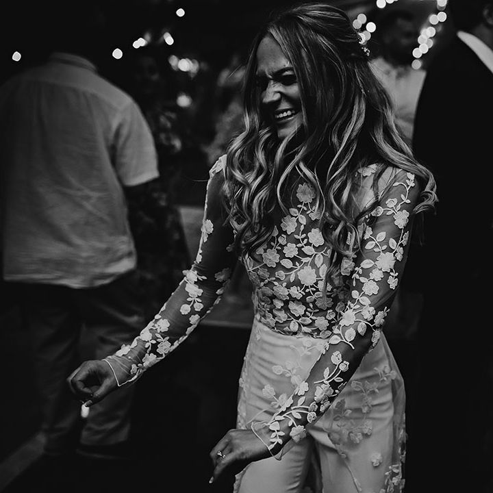 Bride in sheer lace top jumpsuit dances at the reception 
