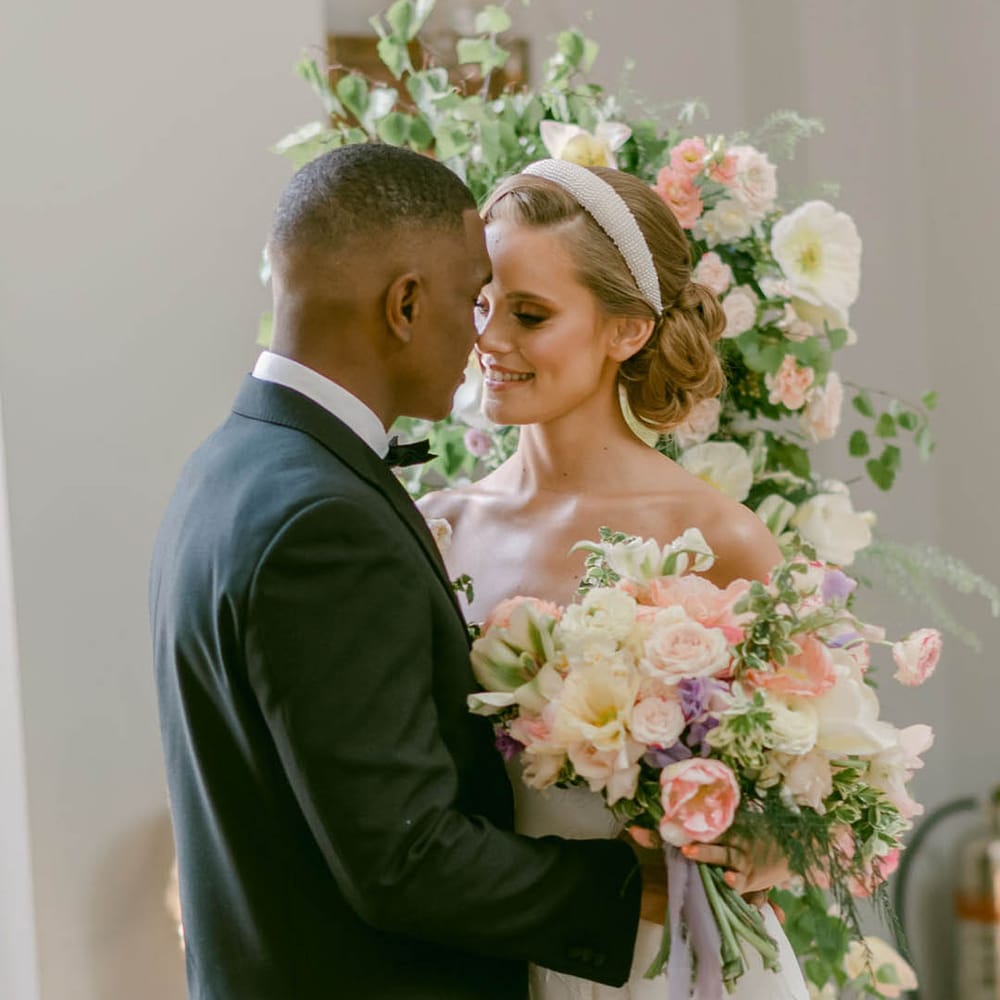 Groom in black tie for Manor House wedding with bride smiling at him in a strapless wedding dress 