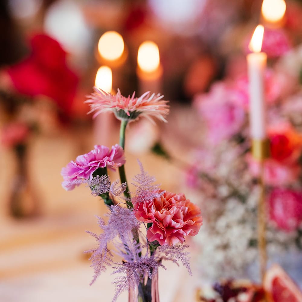 Small brightly coloured floral arrangement in purple vase