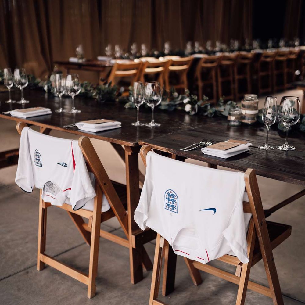 Football T shirts on the back of chairs at wedding reception used as memorable decorations at DIY wedding