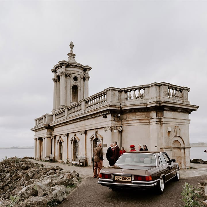 Gothic Normanton Church with the bride and groom exiting from the dark brown Mercedes wedding car with their wedding guests gathering 