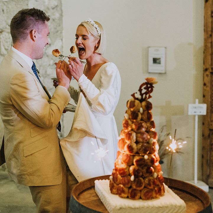 Bride and groom cutting their croquembouche wedding cake at French destination wedding