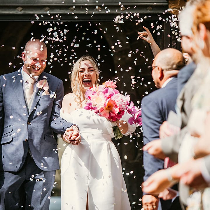 The bride and groom exit their church ceremony to white confetti 