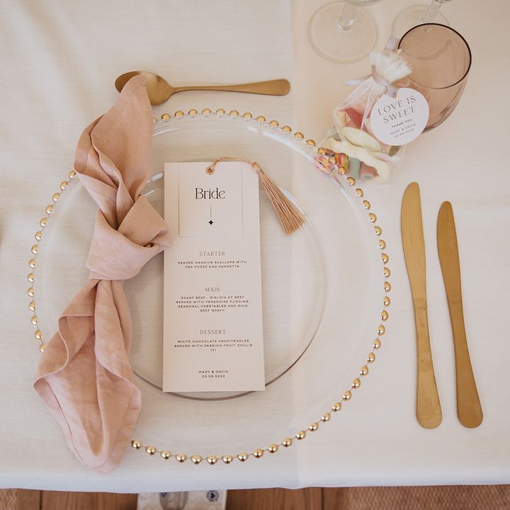 Pink and gold theme wedding place setting with wedding sweet favours and gold charger plate 