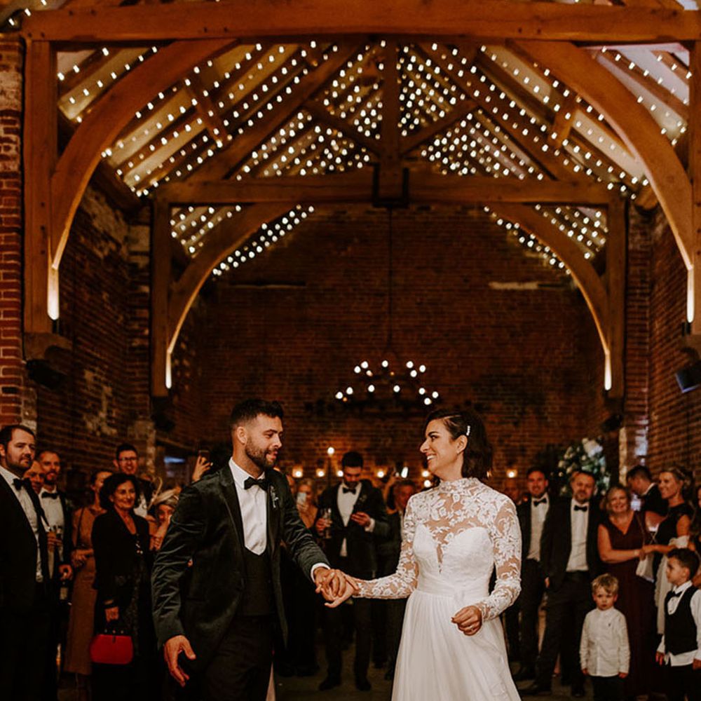 The bride and groom have their first dance together at the Hazel Gap Barn with fairy lights and white drapery 