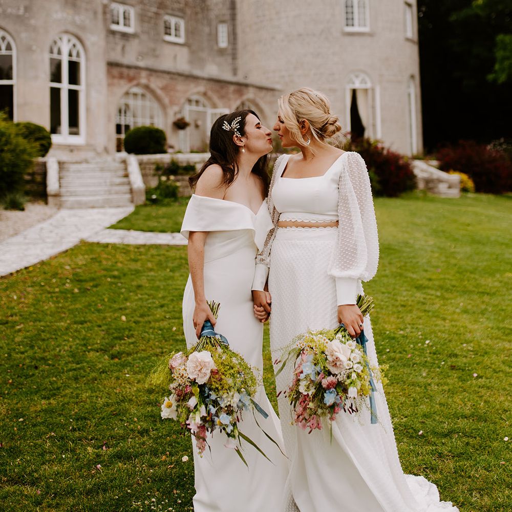 Two brides kiss in front of Pennsylvania Castle Estate wedding venue in the South West 