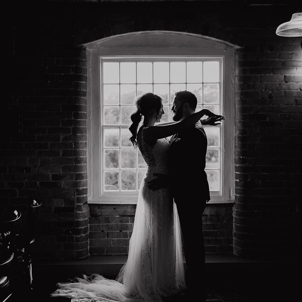 Black and white couple portrait of bride and groom posing in front of a window 