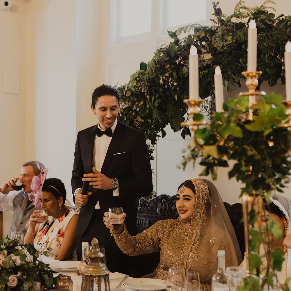 Groom speech at wedding reception filled with botanical plants and flowers 