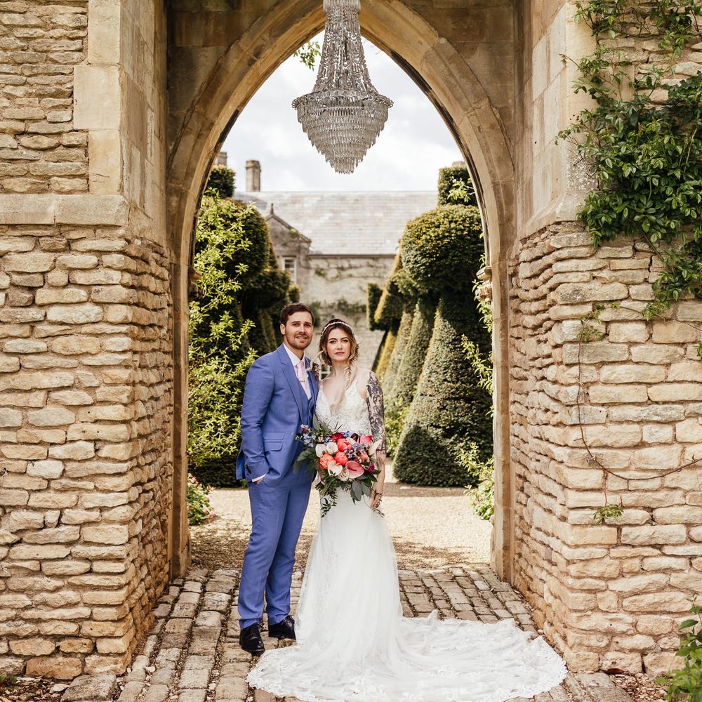 Bride & groom stand beneath archway at Euridge Manor on wedding day