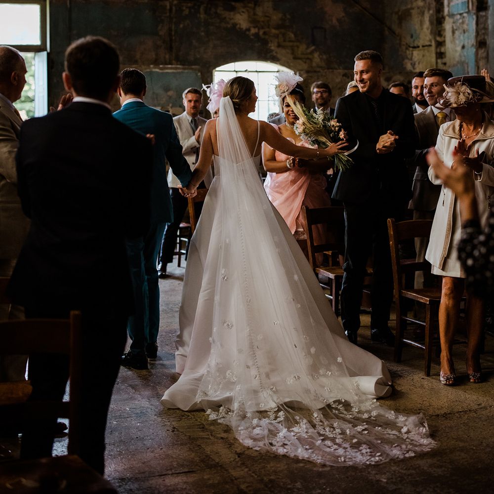 Bride in buttoned wedding dress and long 3D flower veil at chapel wedding