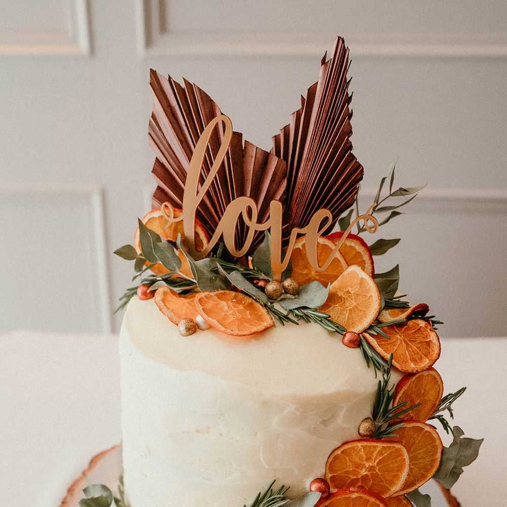 White wedding cake with orange slices and burnt orange embellishments 